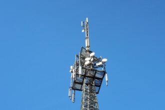 Вежа мобільного зв’язку з антенами на тлі чистого блакитного неба