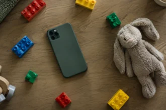 Смартфон серед кольорових кубиків поруч із м’яким іграшковим зайцем