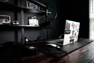Сучасний робочий стіл з нетбуком, мікрофоном і камерою на полиці