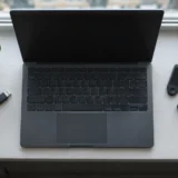 Темний ноутбук на підвіконні поруч із флешкою, плеєром і навушниками