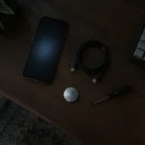 Темний деревʼяний стіл з телефоном, кабелем, викруткою і клавіатурою