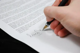 Рука підписує юридичний документ чорнильною ручкою
