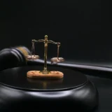 Молоток судді на фоні ваг правосуддя в залі