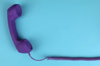 Фіолетова провідна трубка телефону на синьому тлі, мінімалізм
